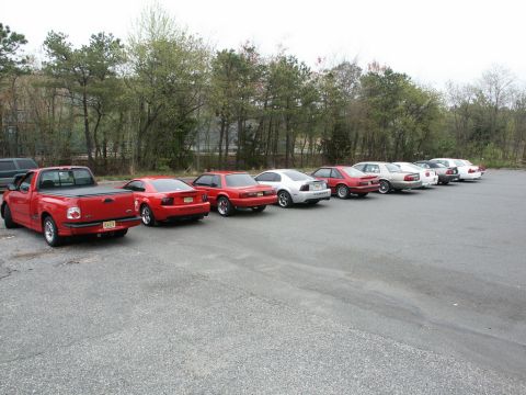 2001 Mercury Grand Marquis - A lineup of red and white vehicles, including a pickup truck and several cars, are parked in an outdoor lot.