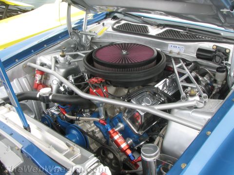 1968 Ford Mustang - The engine bay of a 1968 Ford Mustang shows a powerful V8 engine with custom modifications and a blue paint scheme.