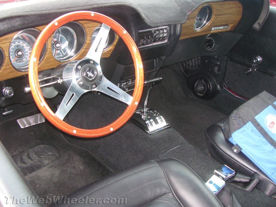 Interior view of a 1969 Mustang Mach 1 with wood grain dash and aftermarket steering wheel