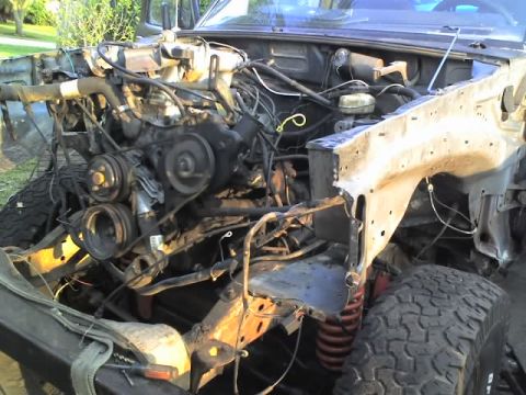 1995 Ford Bronco - The engine bay of a vehicle is shown with many parts removed, revealing the engine and chassis.