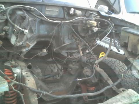 1995 Ford Bronco - The engine bay of a vehicle is shown with many wires and hoses disconnected.