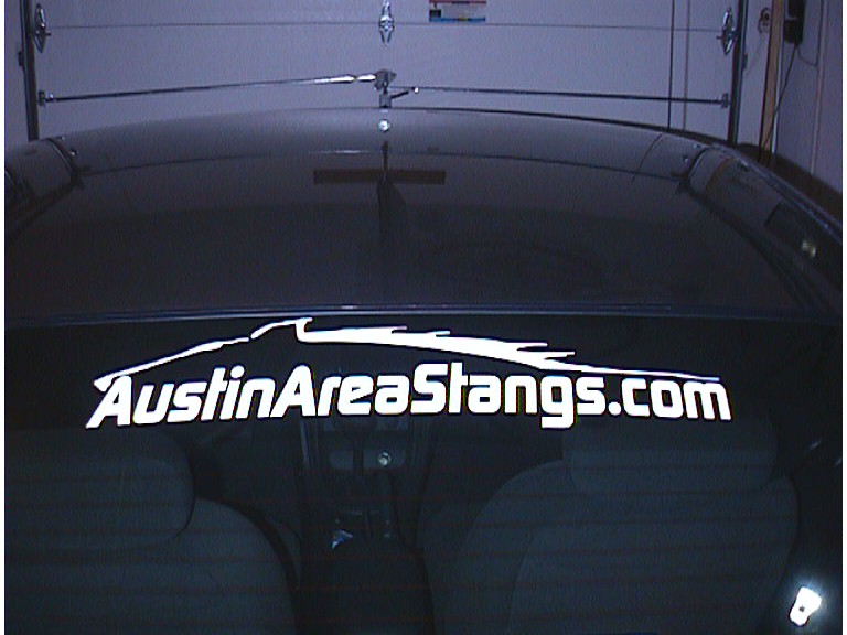White AustinAreaStangs.com decal across the top of a car's rear glass in a garage