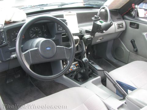 1968 Ford Mustang - The interior of a car shows a manual transmission, CB radio, and Ford steering wheel, suggesting a model from the late 1980s.