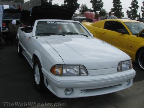 1968 Ford Mustang - A white convertible with an ASC McLaren sticker on the windshield is parked next to a yellow car.