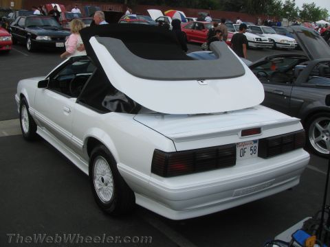 1968 Ford Mustang - A white convertible Mustang is parked at an outdoor event with other vehicles and people around.