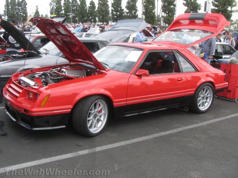 1968 Ford Mustang - This red and black 1985 Ford Mustang coupe is displayed with its hood and trunk open at a car show.