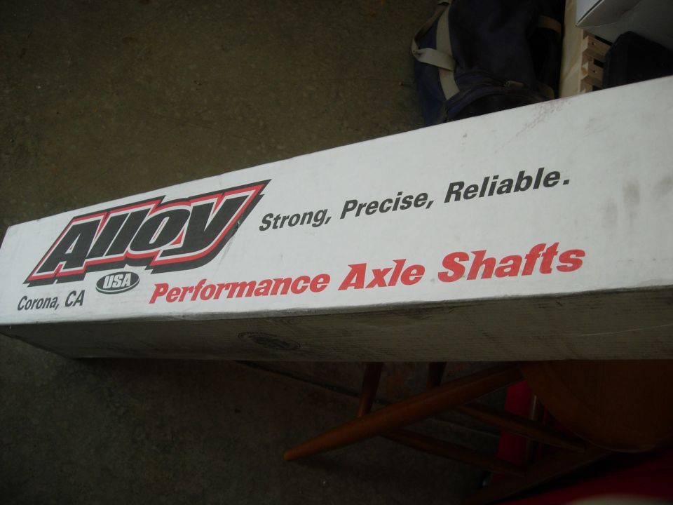 Long white Alloy USA Performance Axle Shafts box sitting on a chair in a garage