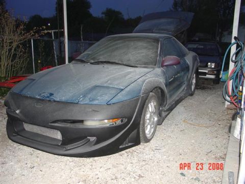 1993 Ford Probe - A dusty blue coupe with pop-up headlights and a car cover is parked in a garage next to another vehicle, with the date April 23, 2008 visib…