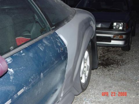 1993 Ford Probe - A car's side panel is covered in primer and body filler, with another vehicle visible in the background.