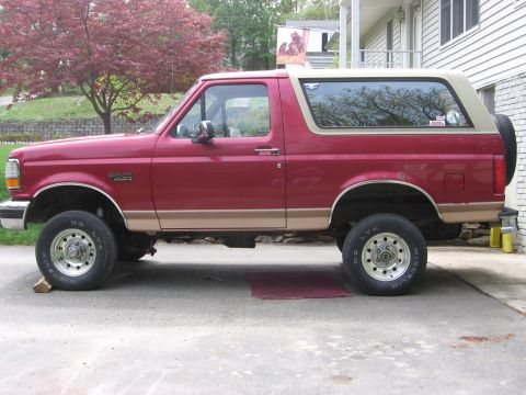 1995 Ford Bronco - This red Ford Bronco features a two-tone tan trim and a spare tire mounted on the rear.