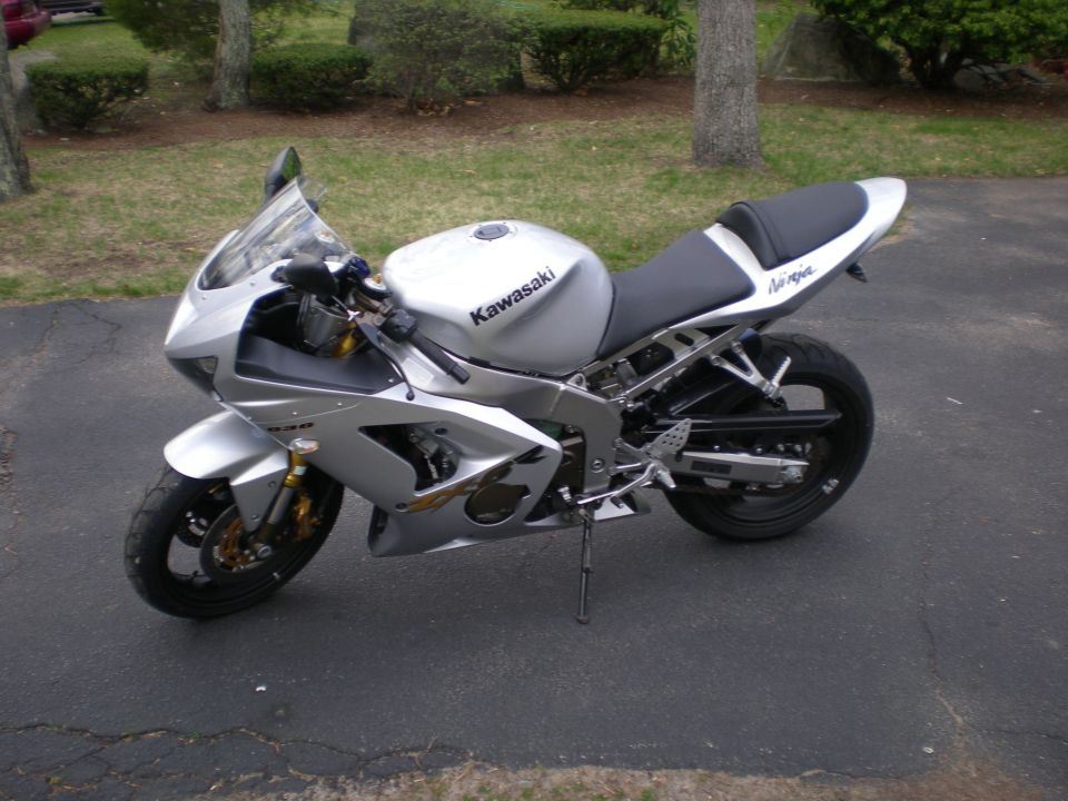 Silver Kawasaki Ninja sportbike parked on driveway, left side view with gold forks