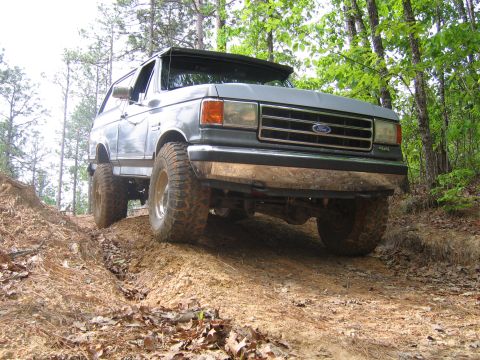 1989 Ford Bronco - 1989 Ford Bronco navigating a muddy trail through the trees.