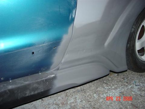 1993 Ford Probe - Side view of a car undergoing bodywork, showing a teal door and a gray fender flare with a wheel.