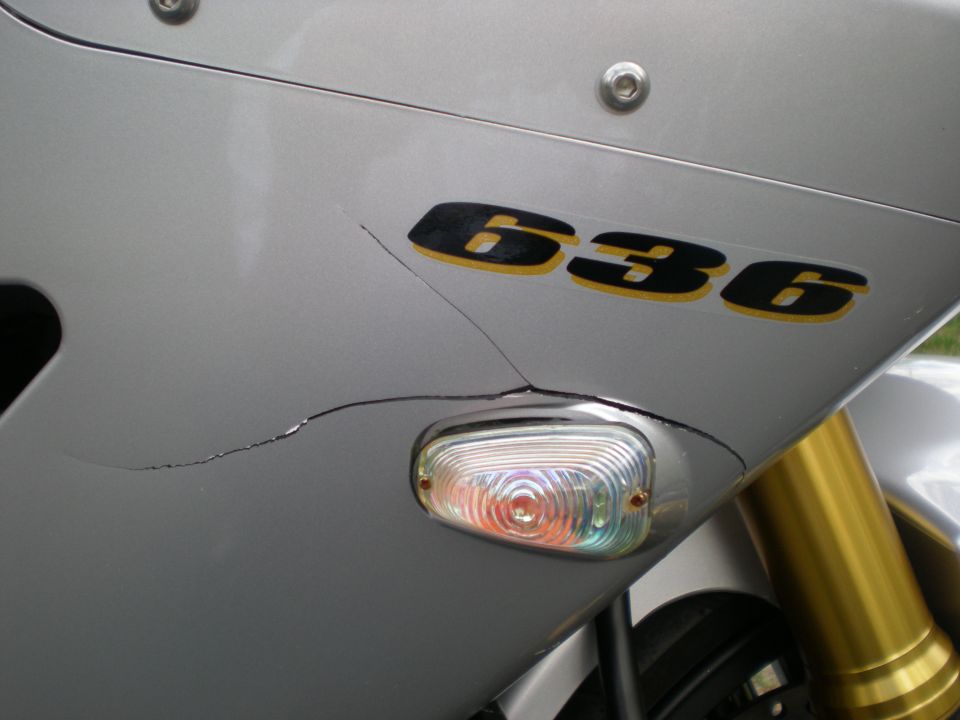 Cracked silver motorcycle fairing with 636 decal and flush oval turn signal, gold forks behind