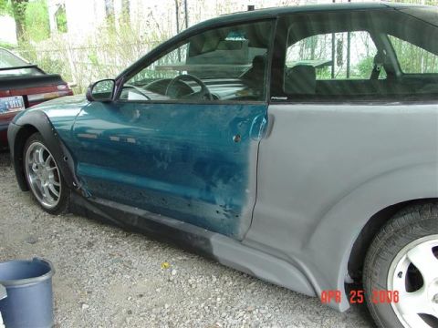 1993 Ford Probe - A car with its rear quarter panel in primer sits next to another vehicle.