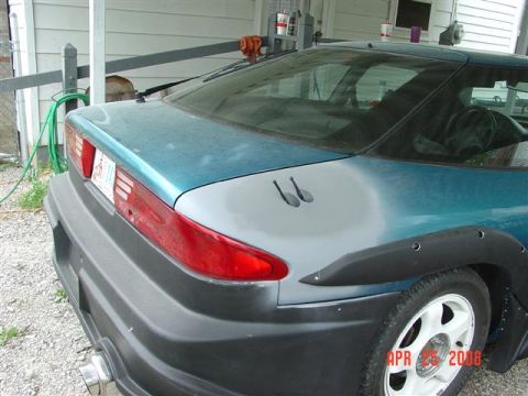 1993 Ford Probe - A teal coupe is shown from the rear quarter, with primer on the fender and black fender flares.