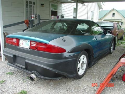 1993 Ford Probe - A teal 1993 Ford Probe with a black body kit is parked next to another car.