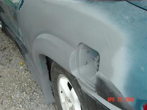 1993 Ford Probe - The rear quarter panel of a car is shown with primer applied and the gas cap door removed, revealing mounting hardware.