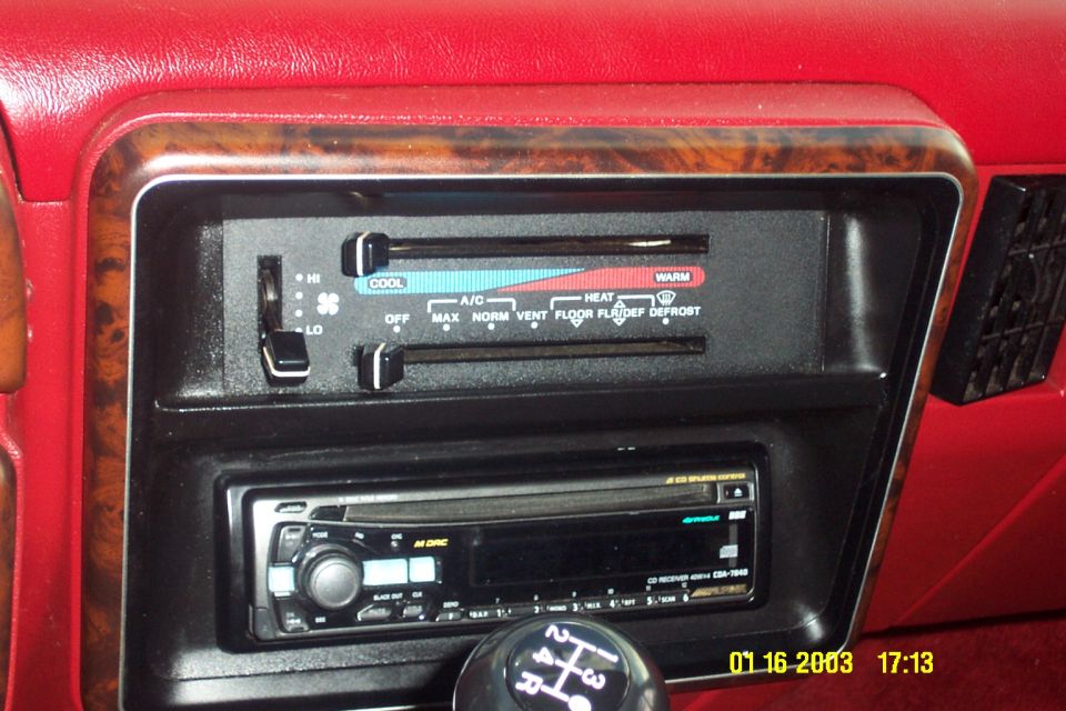 Red truck dash with HVAC slider controls, woodgrain trim, Alpine CD player, and manual shift knob
