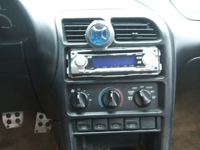 Car center console with aftermarket JVC stereo, rotary HVAC dials, and metal pedals
