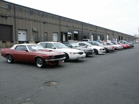 2001 Mercury Grand Marquis - Several cars are parked in a line outside a large industrial building.