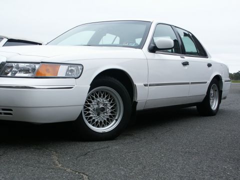 2001 Mercury Grand Marquis - A white 2001 Mercury Grand Marquis is shown from the front quarter angle, custom mesh wheels.