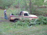 1979 Ford Bronco - A man stands near a vintage pickup truck that appears to be stuck in a muddy, overgrown area.