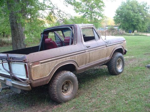 1979 Ford Bronco - This 1979 Ford Bronco, seen in a muddy condition, features a brown and white exterior with a red interior.