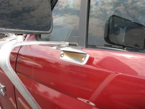 1991 Ford F-150 - The side view mirror and door handle of a red pickup truck are visible in this close-up shot.