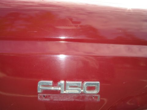 1991 Ford F-150 - Close-up of an F-150 emblem on a red vehicle's side panel.