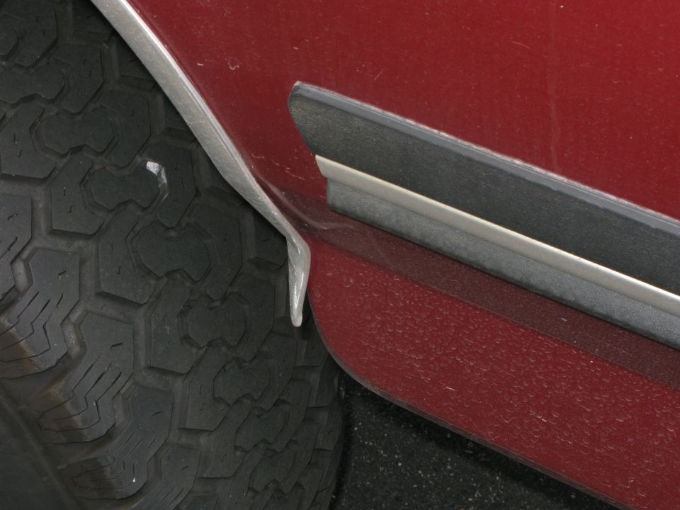 Red vehicle fender trim detail next to tire tread