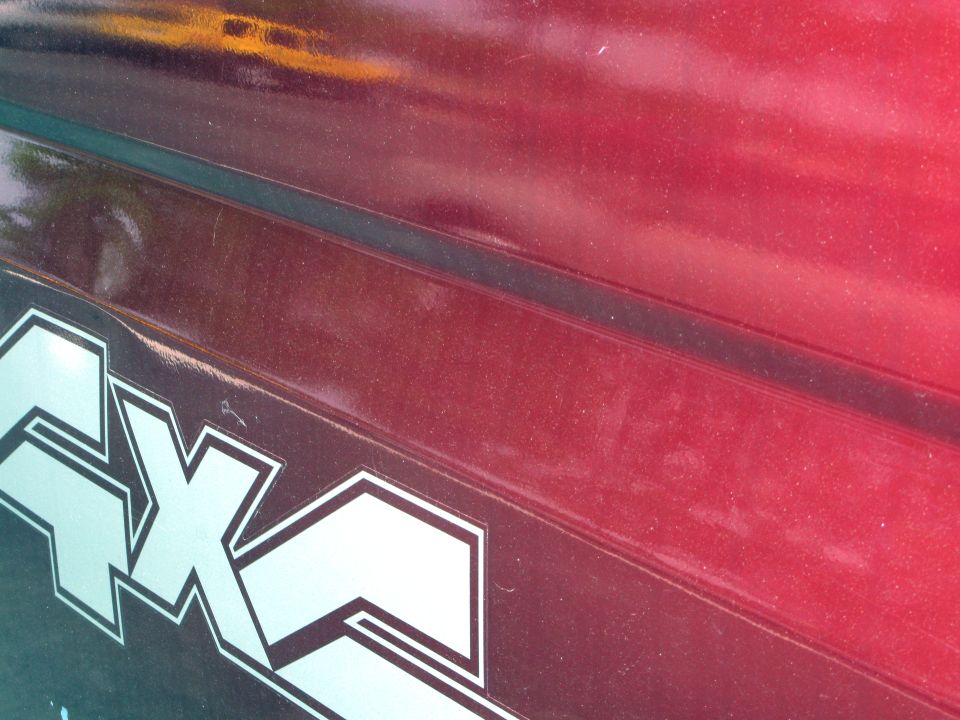 Close-up of a silver 4x4 decal on a red vehicle's body panel