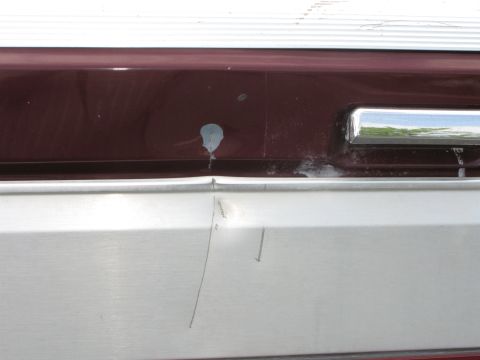 1991 Ford F-150 - Close-up of a damaged truck bumper, showing dents and a paint chip on the maroon section.