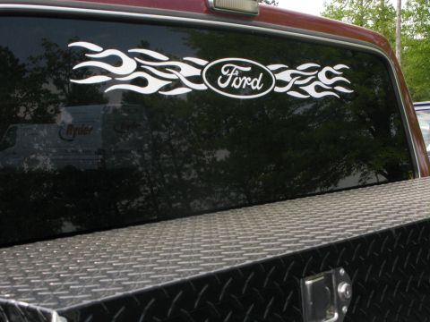 1991 Ford F-150 - Truck rear window features a Ford oval and flame sticker; a Ryder van is reflected.