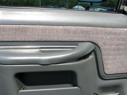 1991 Ford F-150 - The interior door panel of a truck features a plaid fabric insert and a gray pull handle.