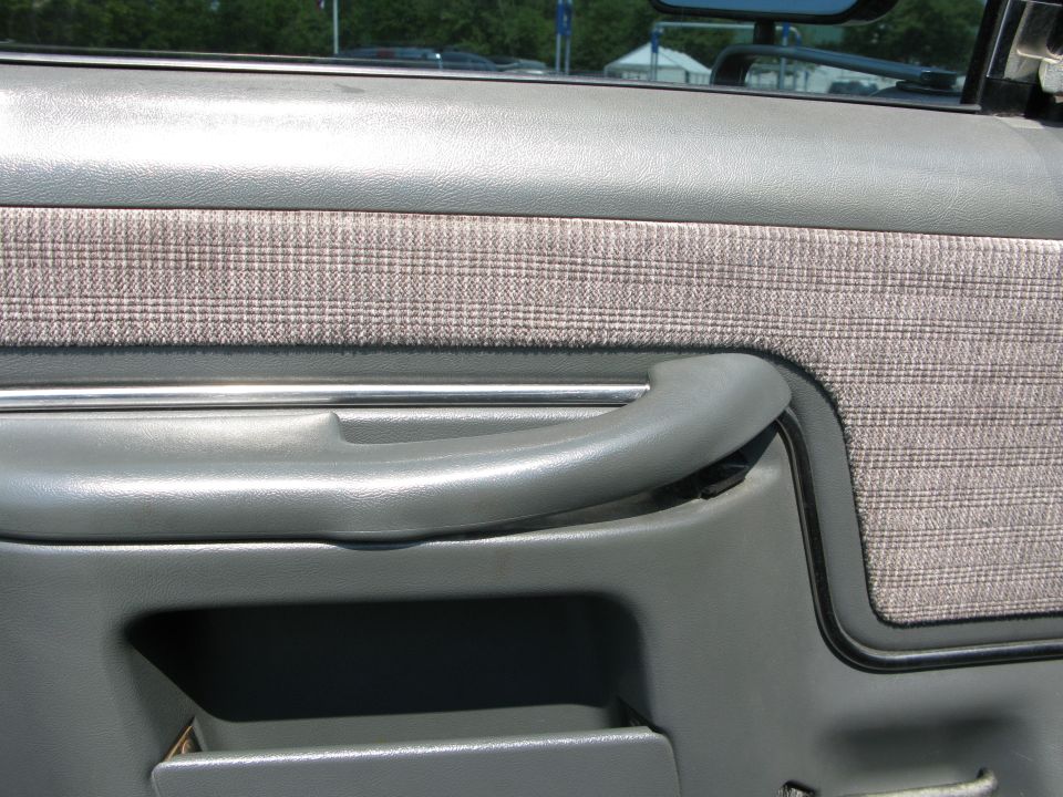 Close-up of a gray truck door panel with a plaid fabric insert and a gray handle