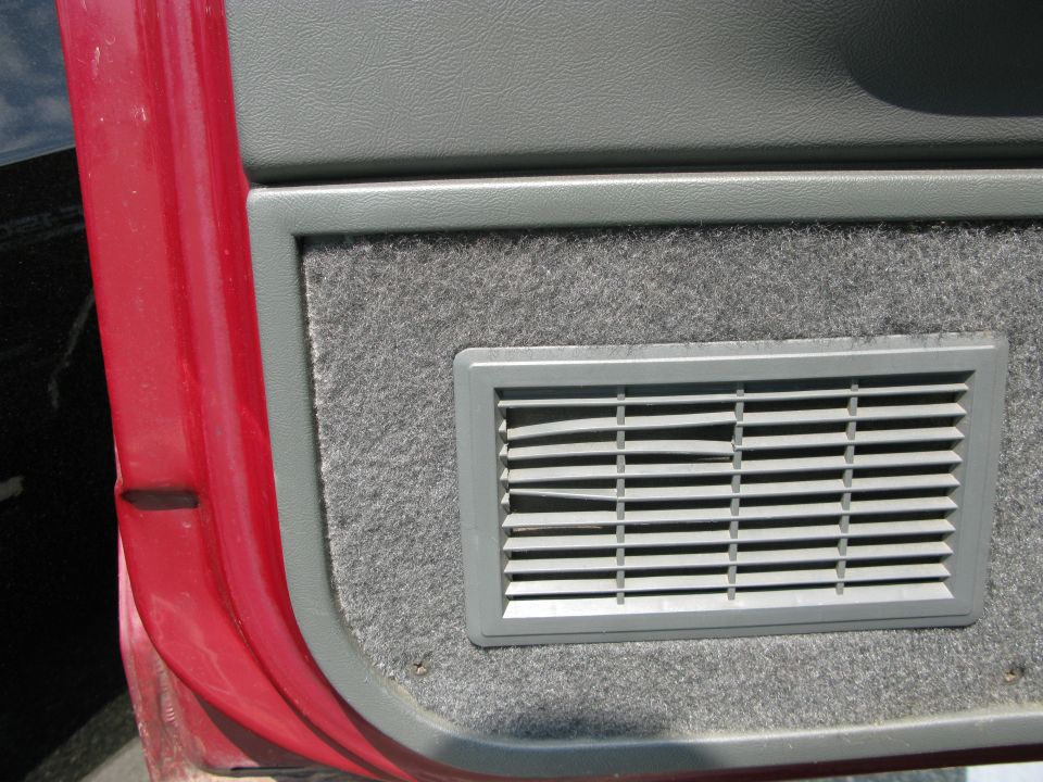 Red car door and gray interior panel with a vent. Watermark "SUPERMOTORS.NET" visible