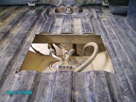 1990 Ford Bronco - The fuel pump assembly is visible after an access panel was removed from the vehicle's underside.