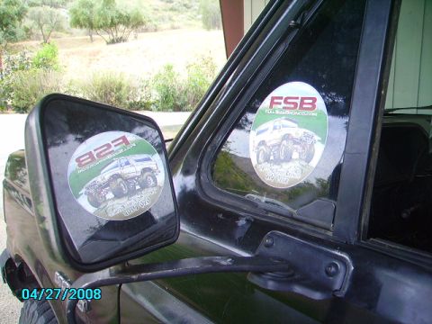 1990 Ford Bronco - A black Ford Bronco is seen from the side, with stickers on the window and mirror reflecting off-road images.
