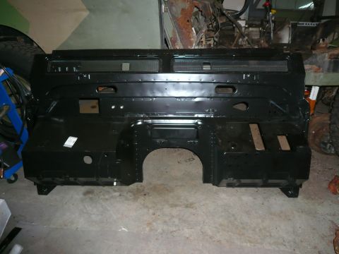 1974 Land Rover Land Rover - A black metal firewall part, likely for a vehicle rebuild, is shown in a workshop setting.