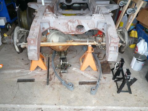 1974 Land Rover Land Rover - The chassis of a vehicle is disassembled and supported by jack stands, with parts laid out for restoration.