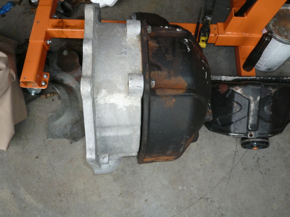 Removed gearbox with cast aluminium housing and rusty bell housing on a garage floor