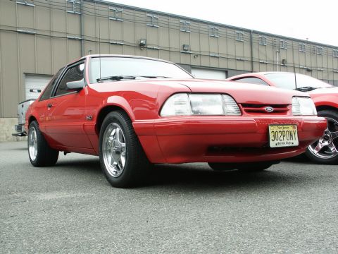2001 Mercury Grand Marquis - Red Ford Mustang parked outside a building, with another vehicle visible behind it.