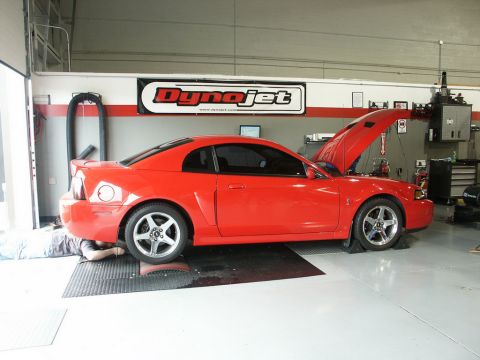 2001 Mercury Grand Marquis - A red Ford Mustang is positioned on a dynamometer in a workshop, with its hood open and a person working underneath.