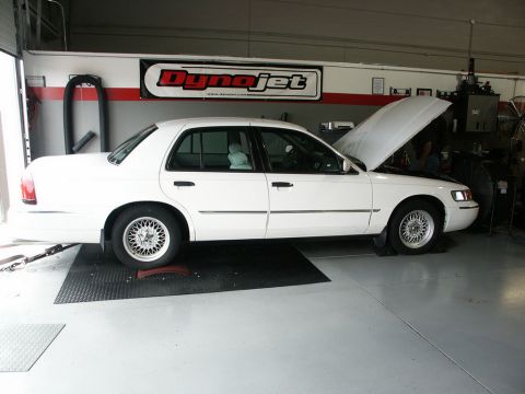 2001 Mercury Grand Marquis - White 2001 Mercury Grand Marquis positioned on a dynamometer with its hood raised, indicating preparation for performance testing.