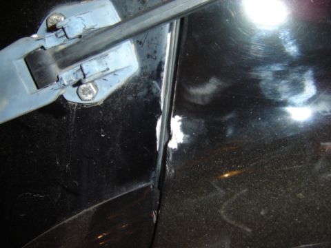 1992 Ford Bronco - Detail shot of a car's door hinge and surrounding bodywork, showing signs of wear and damage.