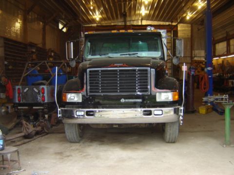 1992 Ford Bronco - A black International truck is parked inside a garage, with another vehicle visible behind it.