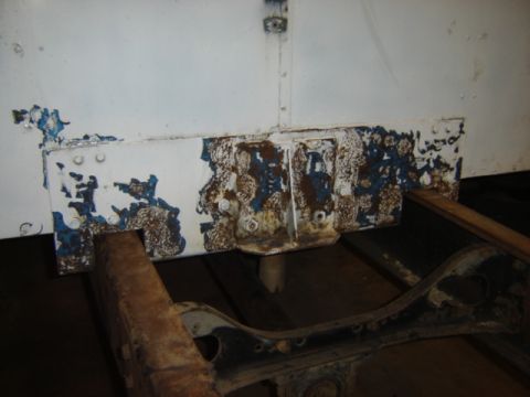 1992 Ford Bronco - Close-up of a heavily rusted and peeling white metal bracket on a vehicle frame.