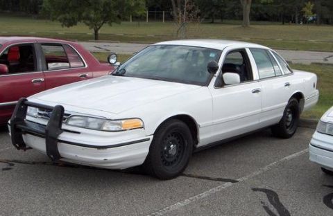 1996 Ford Crown Victoria - A white 1996 Ford Crown Victoria police car is parked next to another vehicle.