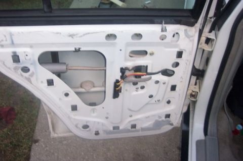 1996 Ford Crown Victoria - The interior of a white car door panel is visible, showing the internal mechanisms and wiring.